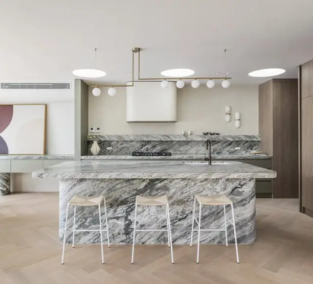 Book matched marble island under sculptural pendants
